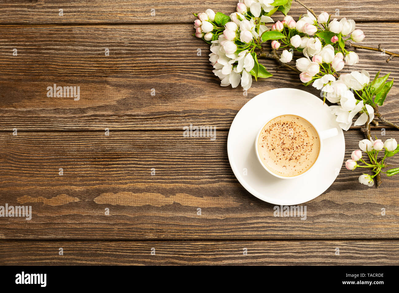 Eine heiße Tasse aromatischen Kaffee und einem blühenden Zweig von einem Apfelbaum auf einer hölzernen Hintergrund. Flache Layout. Stockfoto