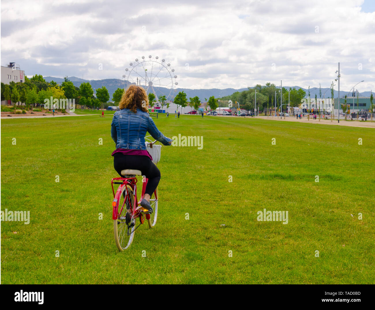 Blonde Frau Fuß in den Park mit einem Blue Denim auf einem roten Fahrrad Stockfoto