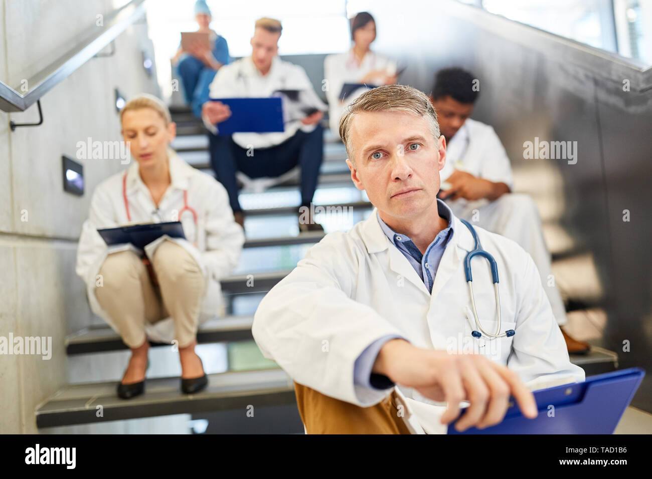 Oberarzt mit Verantwortung und Kompetenz mit seinem medizinischen Team während einer Pause Stockfoto