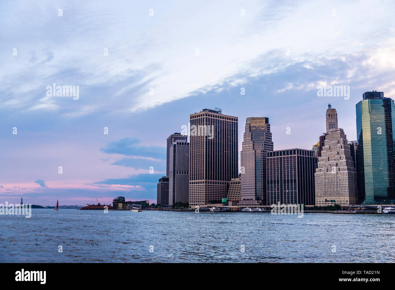 Skyline von modernen Wolkenkratzern von New York Bankenviertel und der Lower Manhattan und die Freiheitsstatue bei Sonnenuntergang von der Brooklyn Brid gesehen Stockfoto