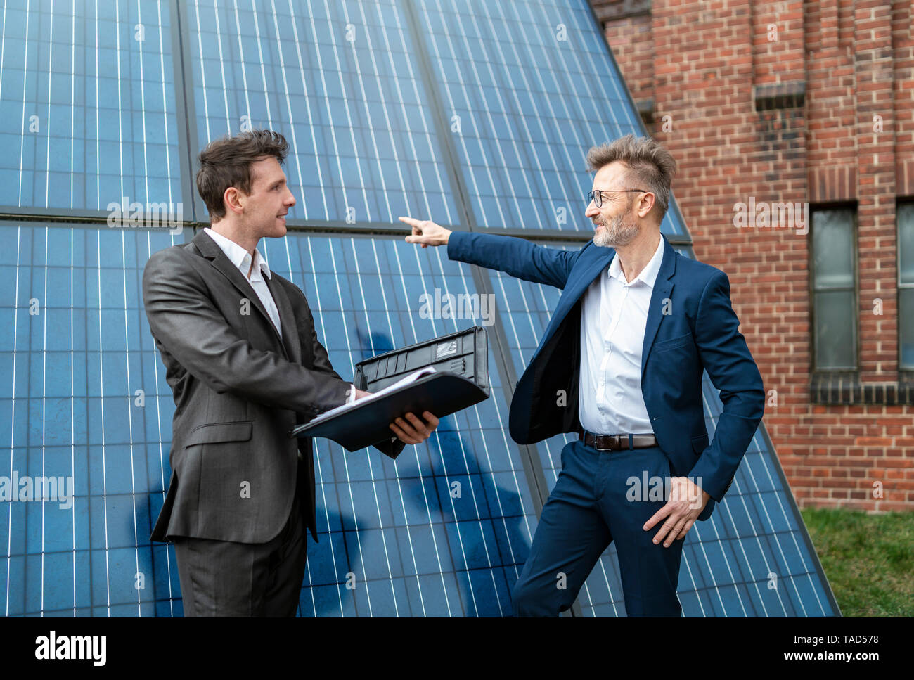 Zwei Geschäftsleute sprechen außerhalb Backsteingebäude auf der Solar Panels Stockfoto