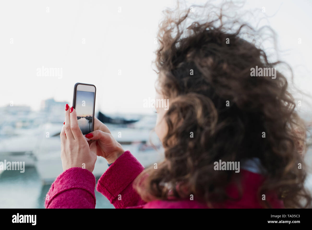 Frau mit lockigem Haar, ein Handy Bild Stockfoto