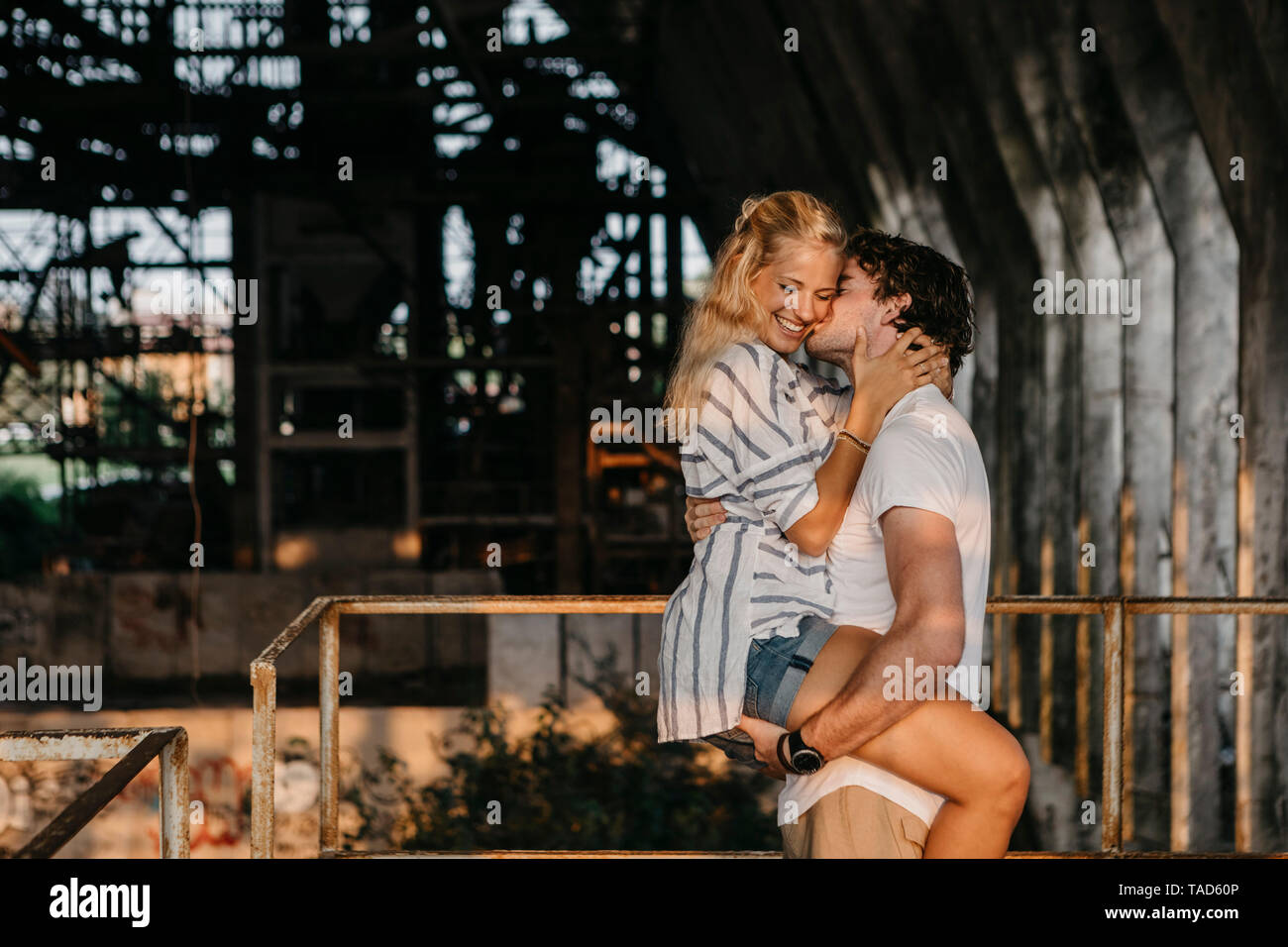 Junger Mann, Küssen und Freundin in einem alten Bahnhof Stockfoto