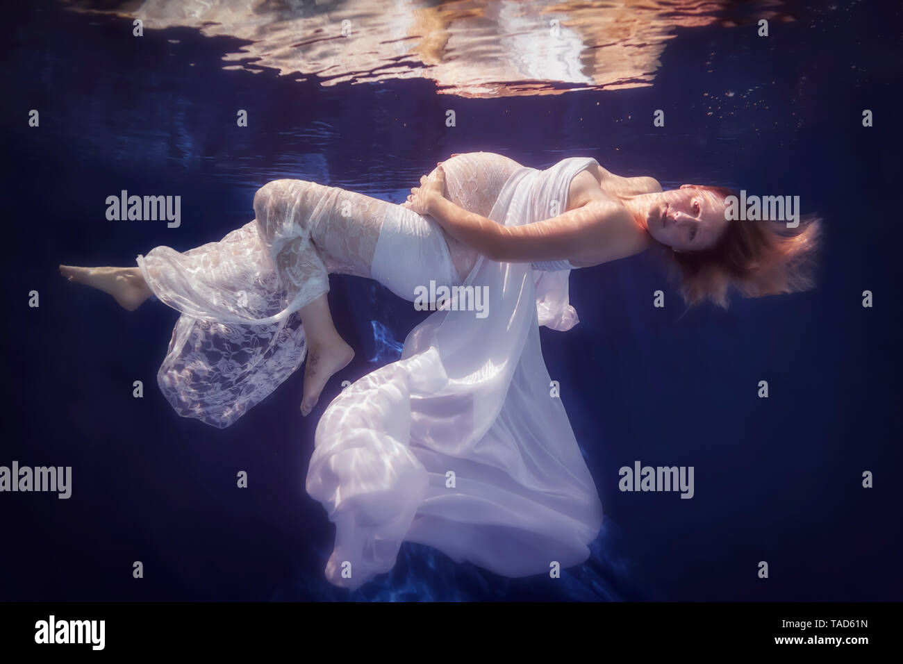 Schwangere Frau tragen weiße Kleid unter Wasser Stockfoto