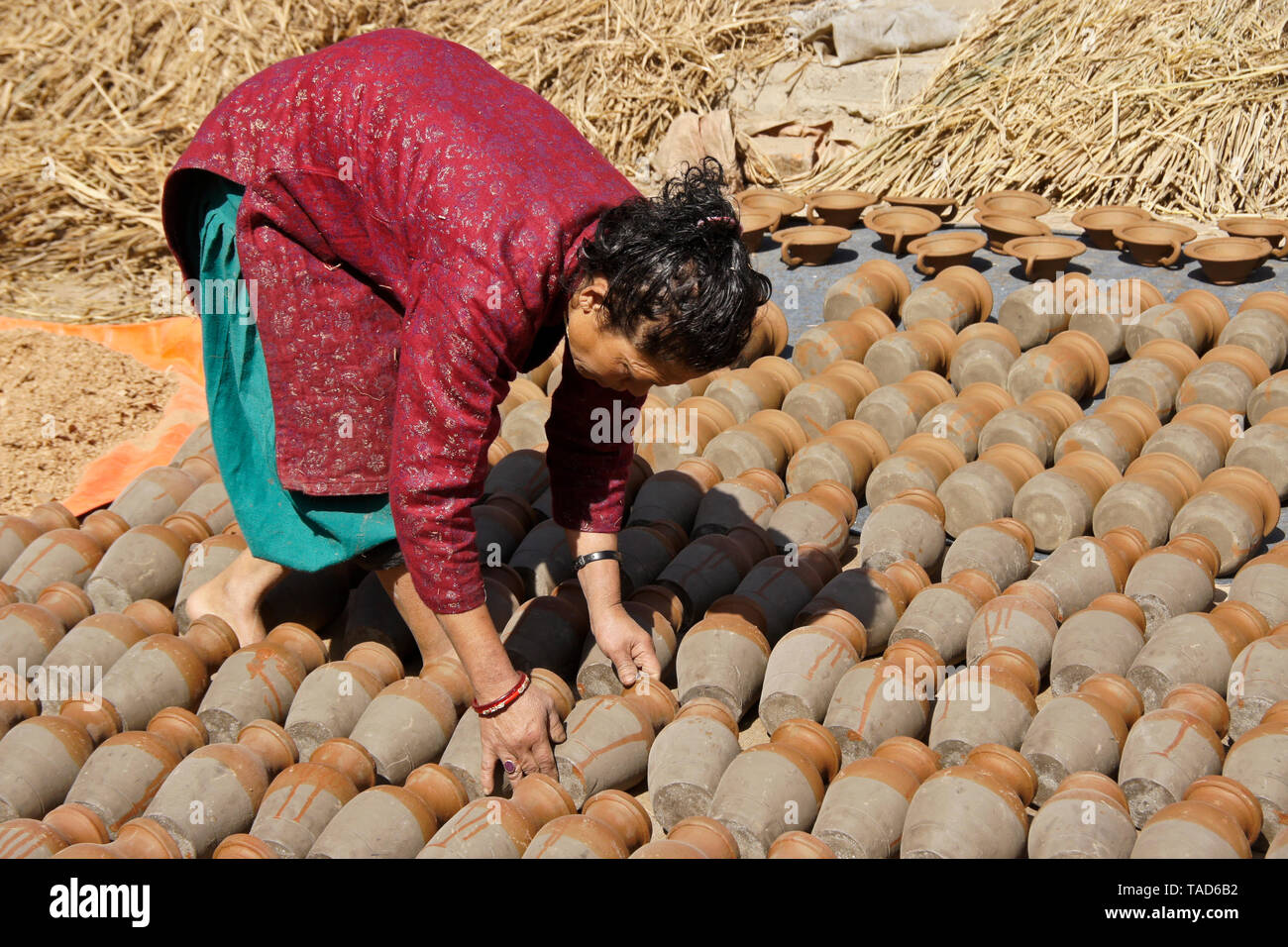 Frau drehen Tongefäße, da sie Sun-dry in Kumale Tol (Töpfern, Keramik), Bhaktapur, Tal von Kathmandu, Nepal Stockfoto