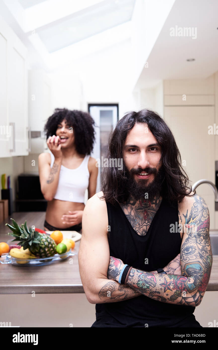 Portrait von lächelnden tätowierten Mann mit Freundin in der Küche Stockfoto