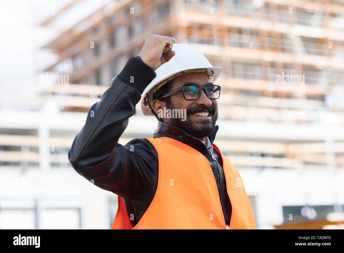 Portrait von glücklichen Konstrukteur vor der Baustelle das Tragen von Helm und Warnweste Stockfoto