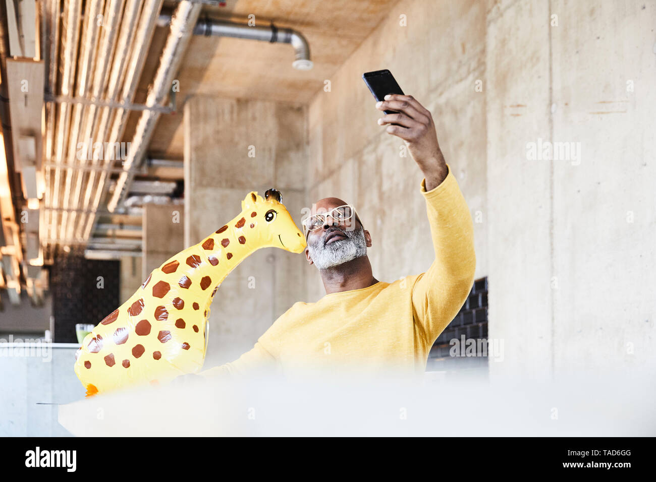 Reifen Geschäftsmann am Schreibtisch im Büro mit giraffe Figur eine selfie Stockfoto