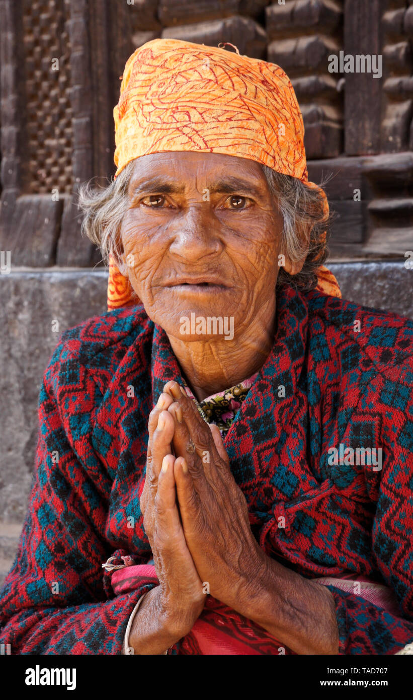 Ältere Frau sitzend mit Handflächen in namaste Gruß, Bhaktapur, Tal von Kathmandu, Nepal Stockfoto