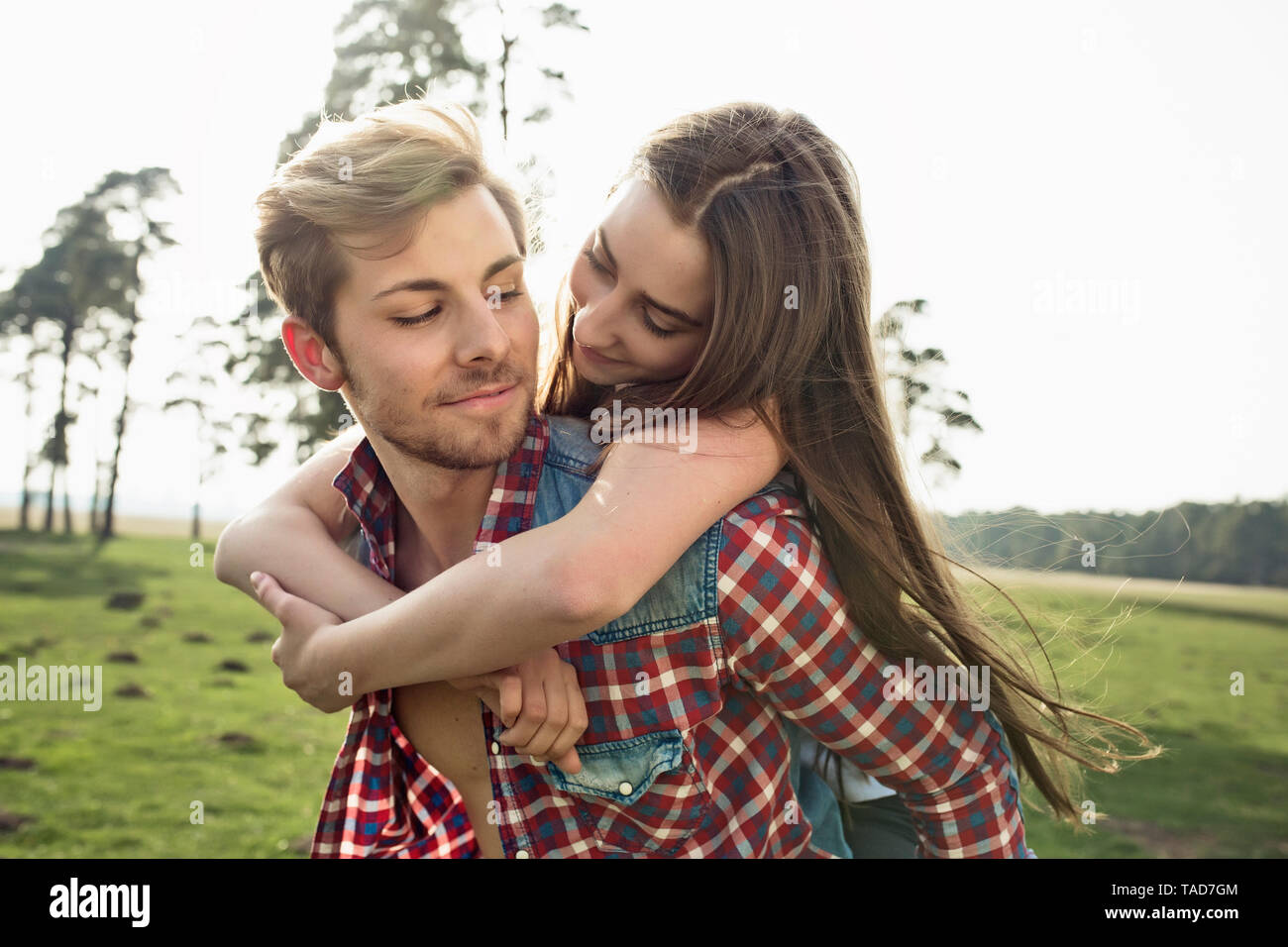 Lächelnden jungen Mann, Freundin Huckepack auf Wiese Stockfoto