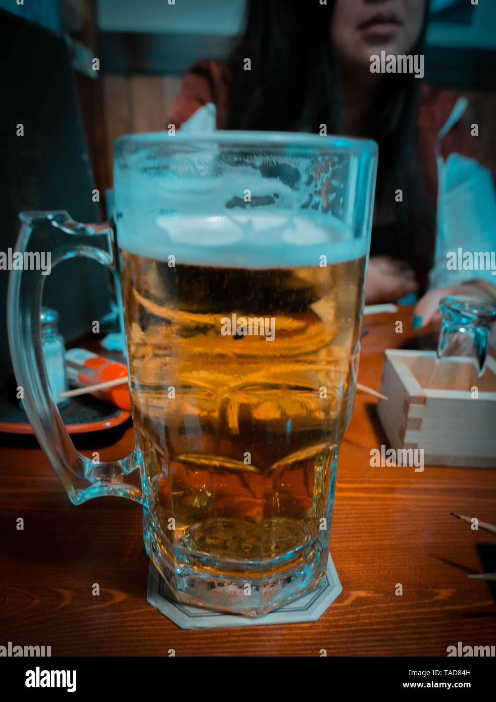 Große Tasse japanischen Lagerbier in einem Restaurant mit einer Frau im Hintergrund Stockfoto