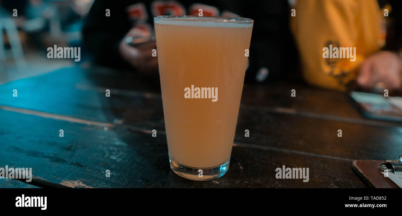 Frontal von einem einzigen Glas indische Pale Ale Bier in einer Bar in San Diego mit Menschen im Hintergrund Stockfoto