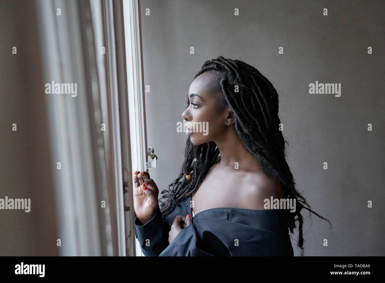Profil von Frau mit Dreadlocks Blick aus Fenster Stockfoto