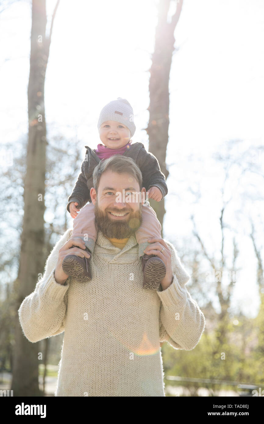 Porträt der glückliche Vater mit Tochter auf Schultern in Park Stockfoto