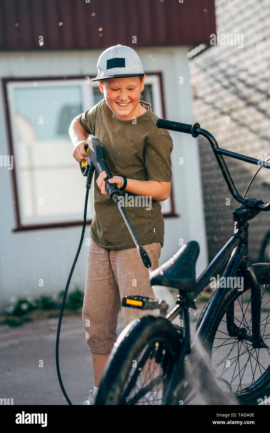Waschen Junge bmx Fahrrad mit Hochdruckreiniger auf Yard Stockfoto