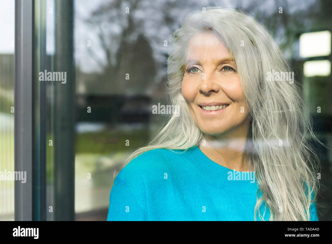 Portrait von Happy reife Frau Blick aus Fenster Stockfoto