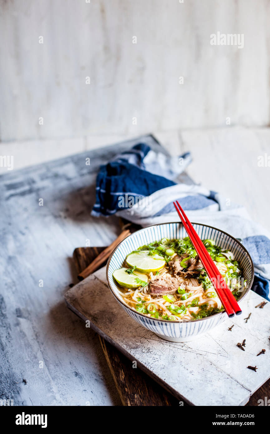 Schüssel mit vietnamesischen Pho mit Reis Nudeln, Mungbohnen, cilantro, Frühlingszwiebeln und Limetten Stockfoto