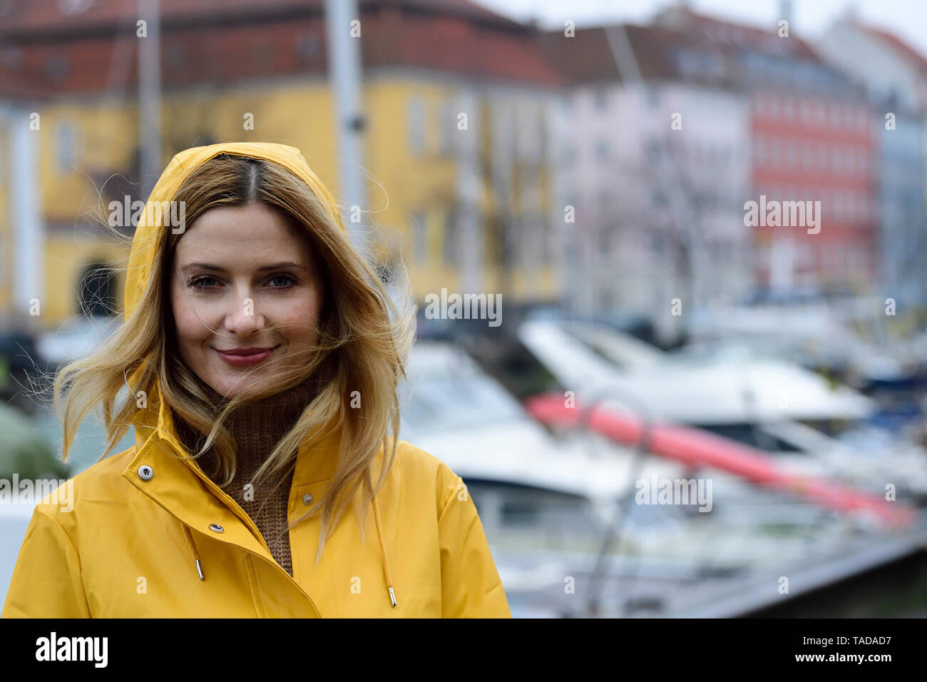 Dänemark, Kopenhagen, Portrait von lächelnden Frau am Hafen der Stadt im regnerischen Wetter Stockfoto