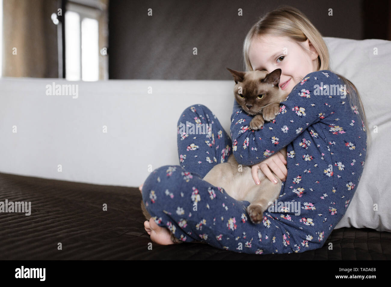 Portrait von lächelnden Mädchen tragen Pyjama mit floralem Design Holding cat Stockfoto
