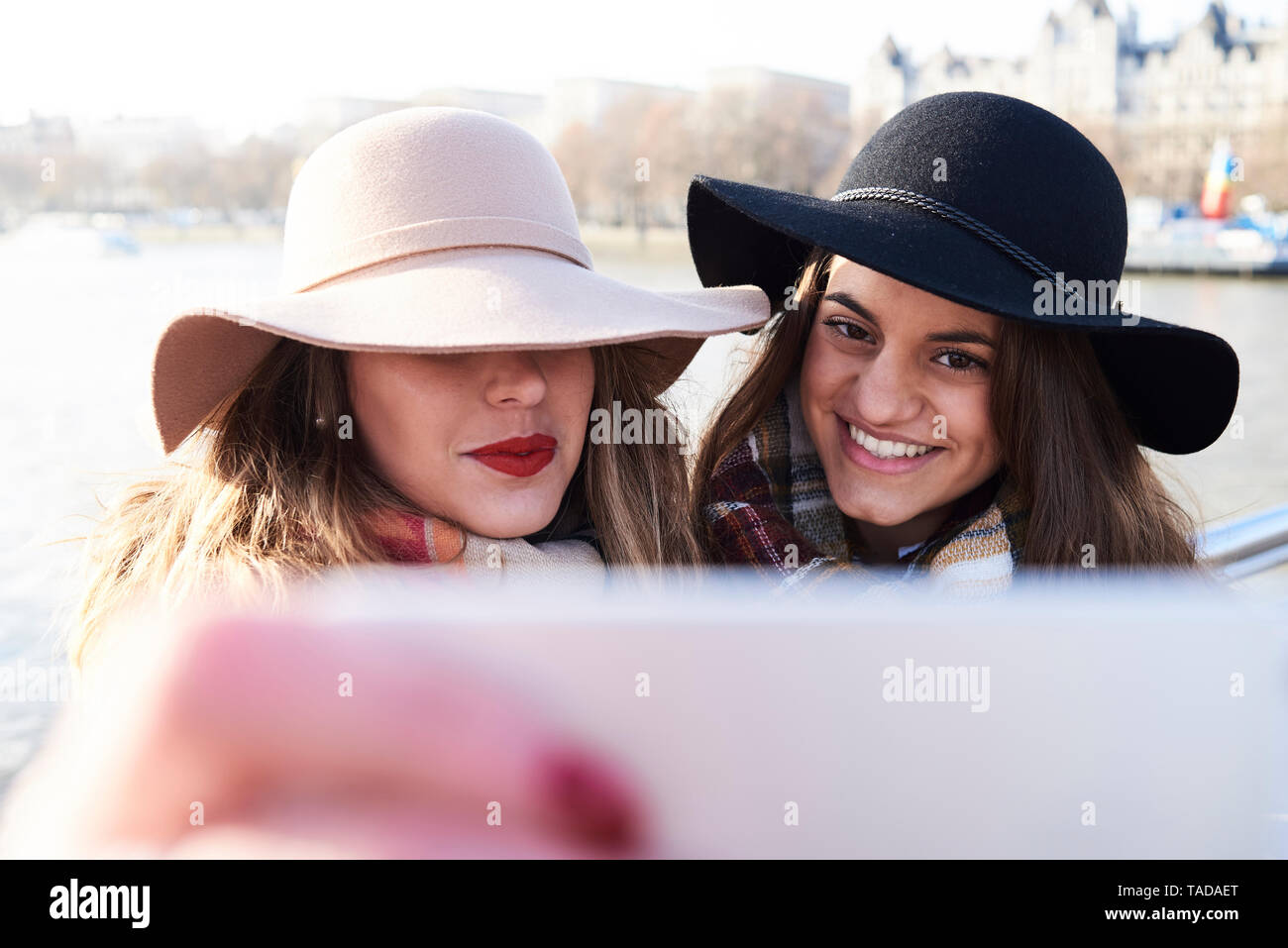 UK, London, zwei Frauen das Tragen von Floppy Hüte ein selfie auf Millennium Bridge Stockfoto