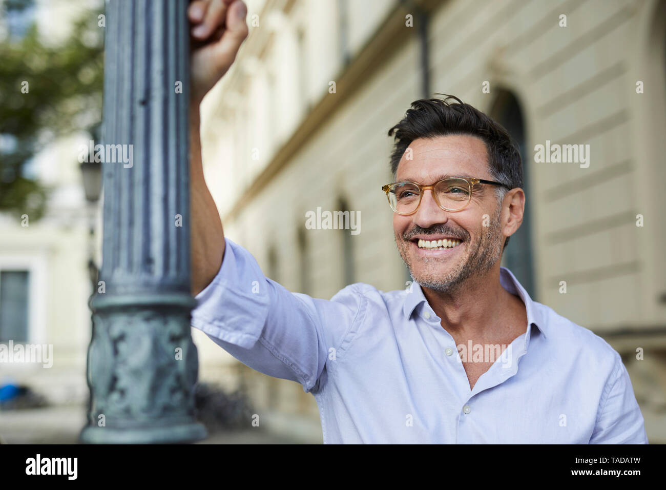 Portrait von Happy Geschäftsmann gegen Lamp Post in der Stadt schiefen Stockfoto