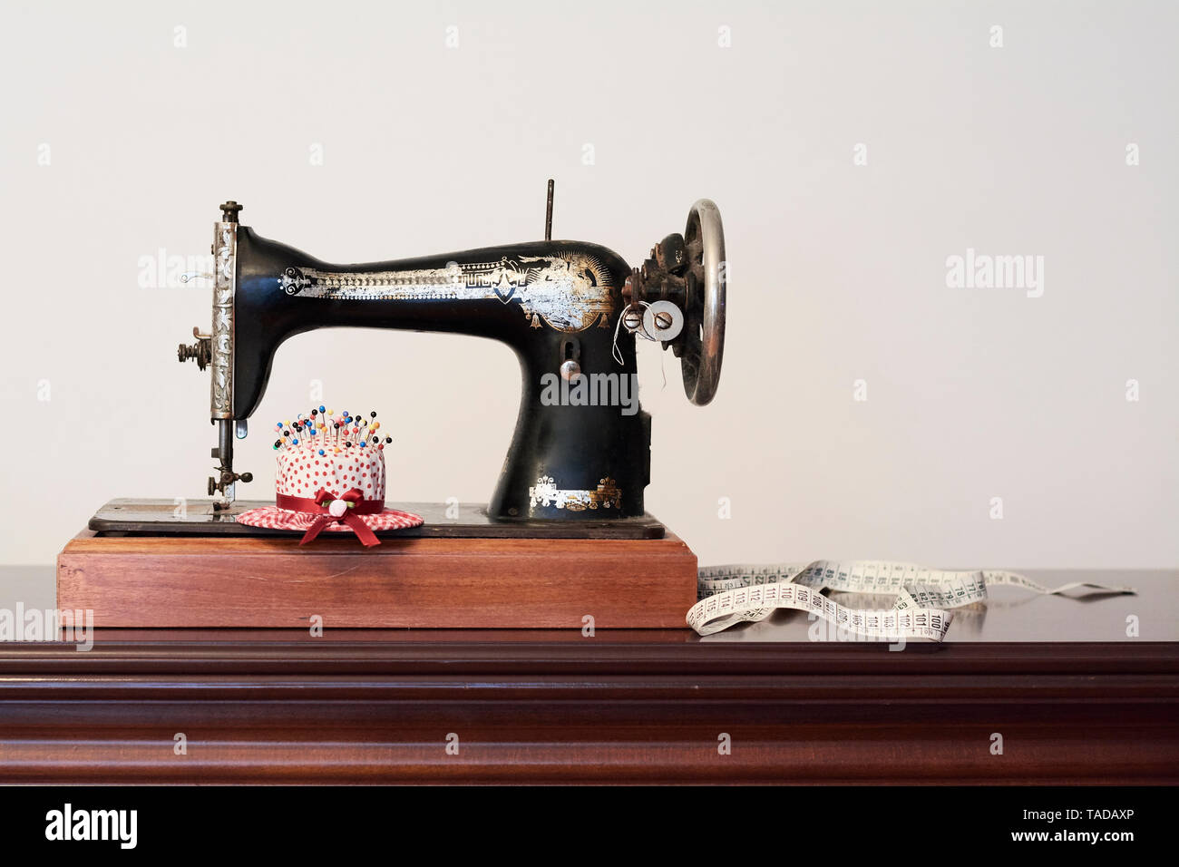 Alte vintage Nähmaschine mit Maßband und Pin chusion in der Form eines Hutes Stockfoto