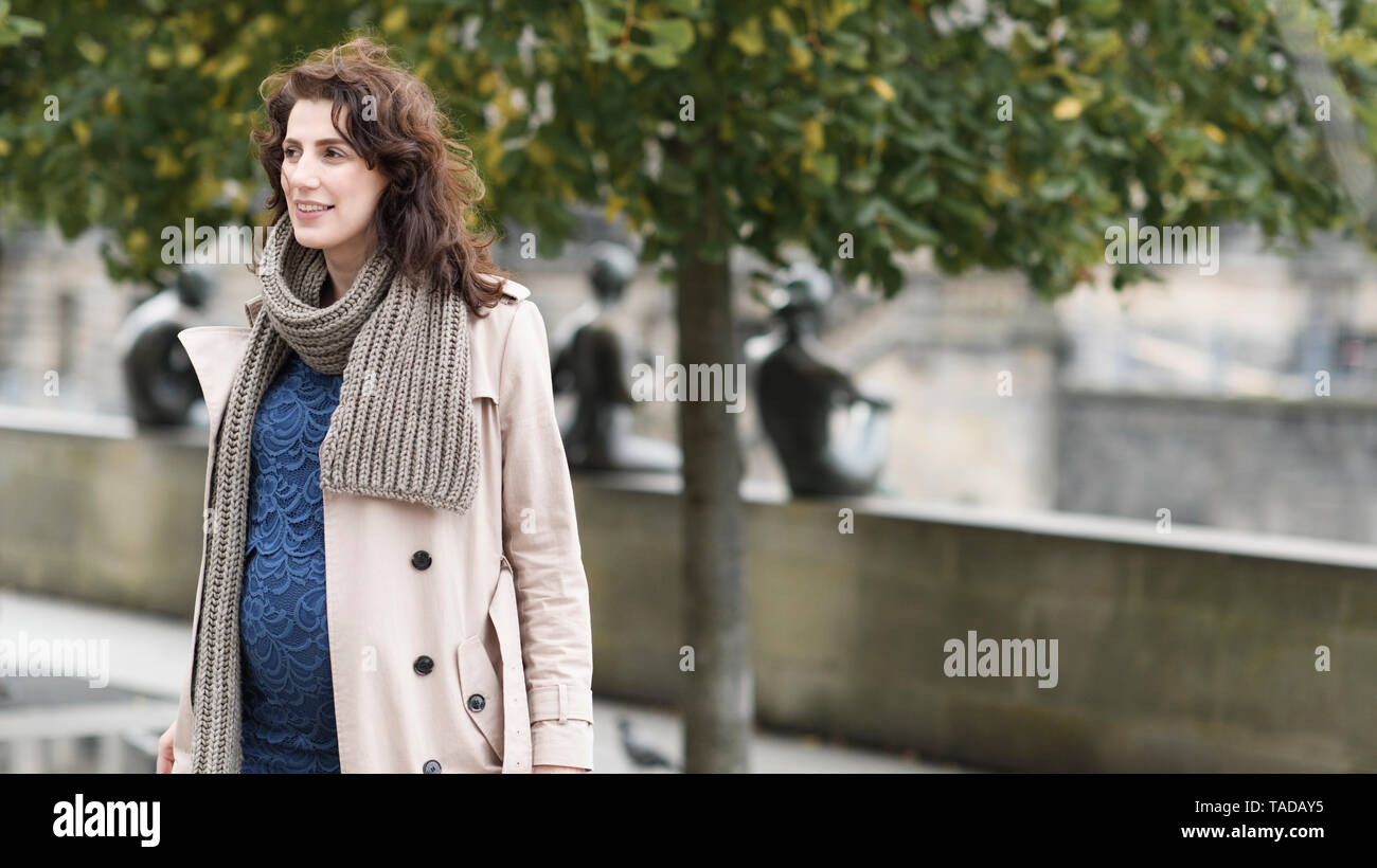 Portrait der schwangeren Frau in Trenchcoat und Schal im Herbst Stockfoto