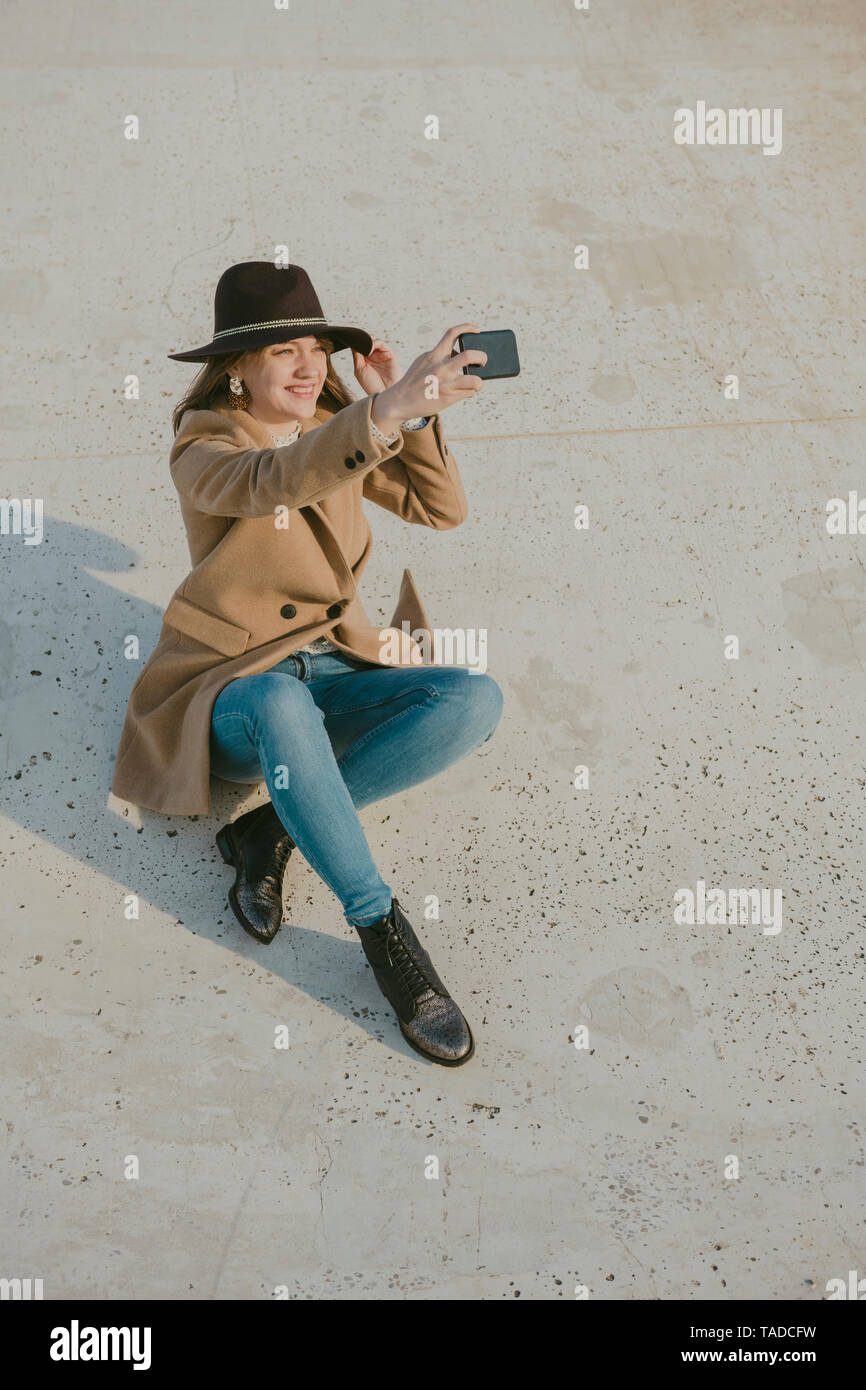 Junge hipster Frau auf dem Boden sitzend einen selfie Stockfoto
