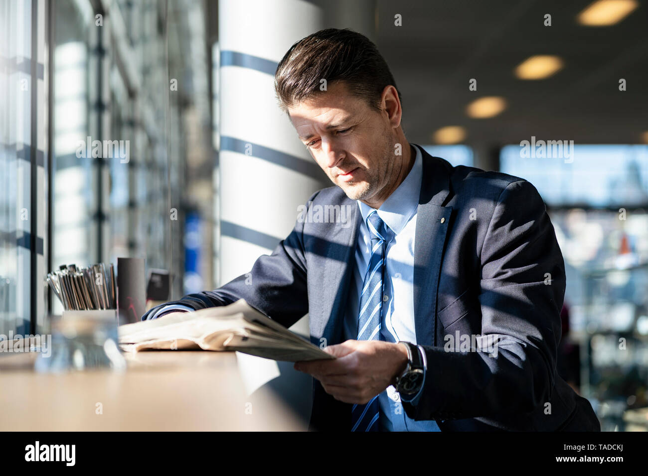 Geschäftsmann lesen Zeitung, die sich am Fenster in einem Cafe Stockfoto