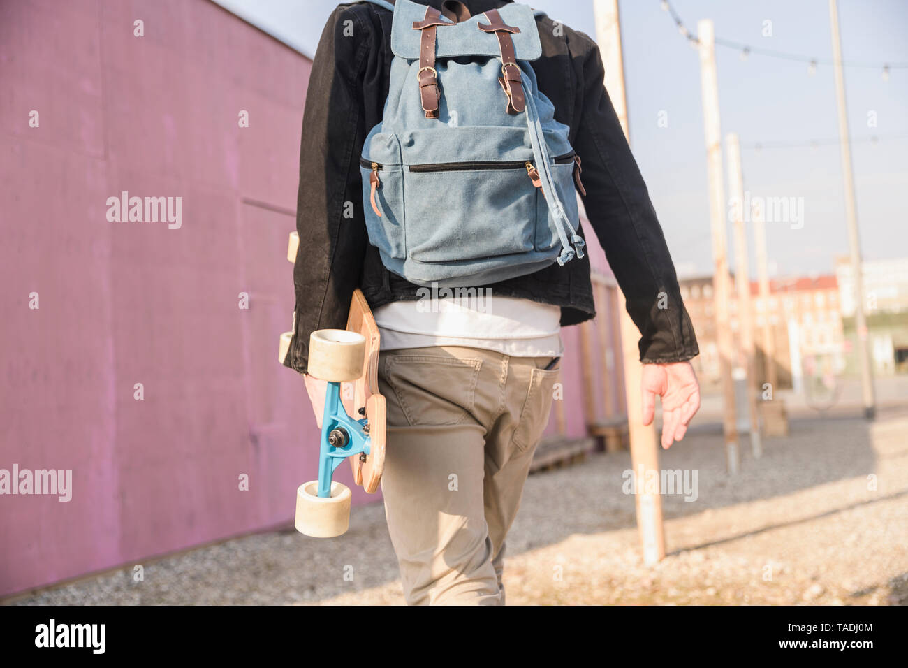 Ansicht der Rückseite des jungen Mannes mit skatebaord und Rucksack unterwegs in der Stadt Stockfoto
