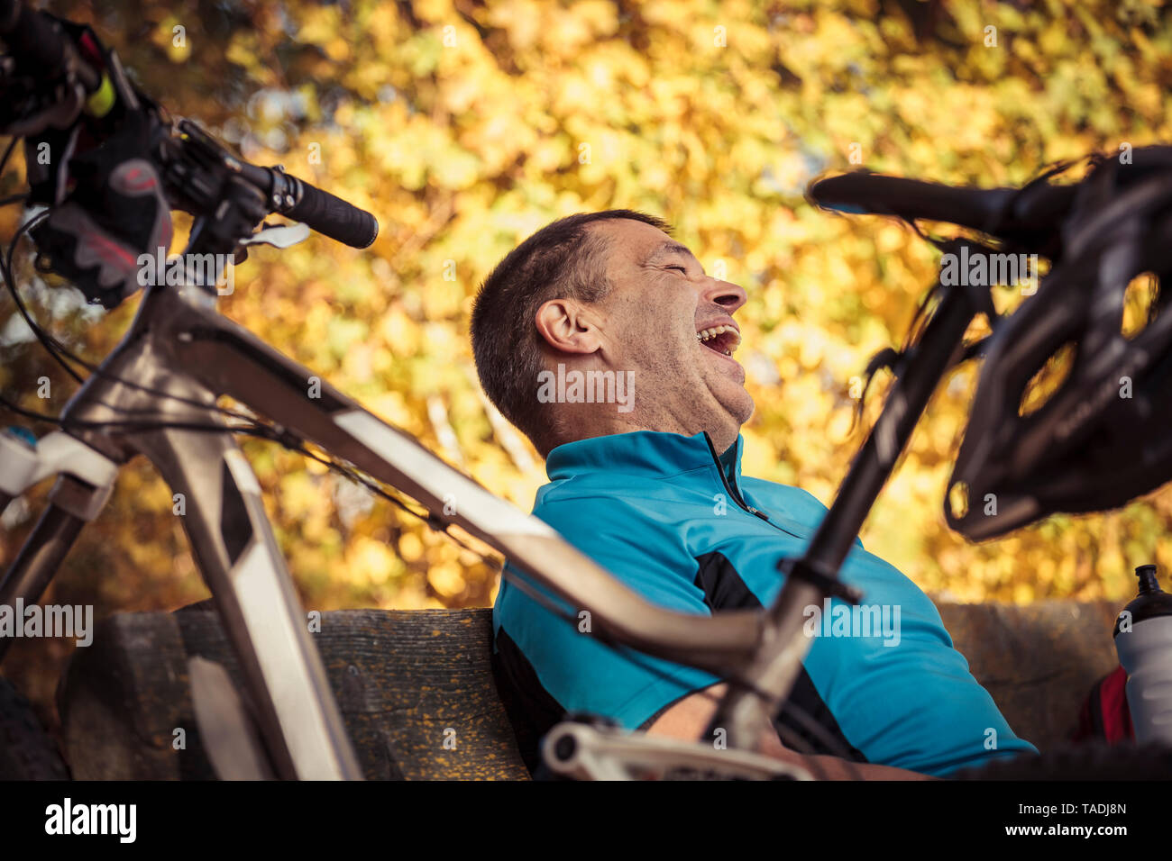 Laughing Man mit dem Mountainbike eine Pause auf einer Bank sitzen  Stockfotografie - Alamy
