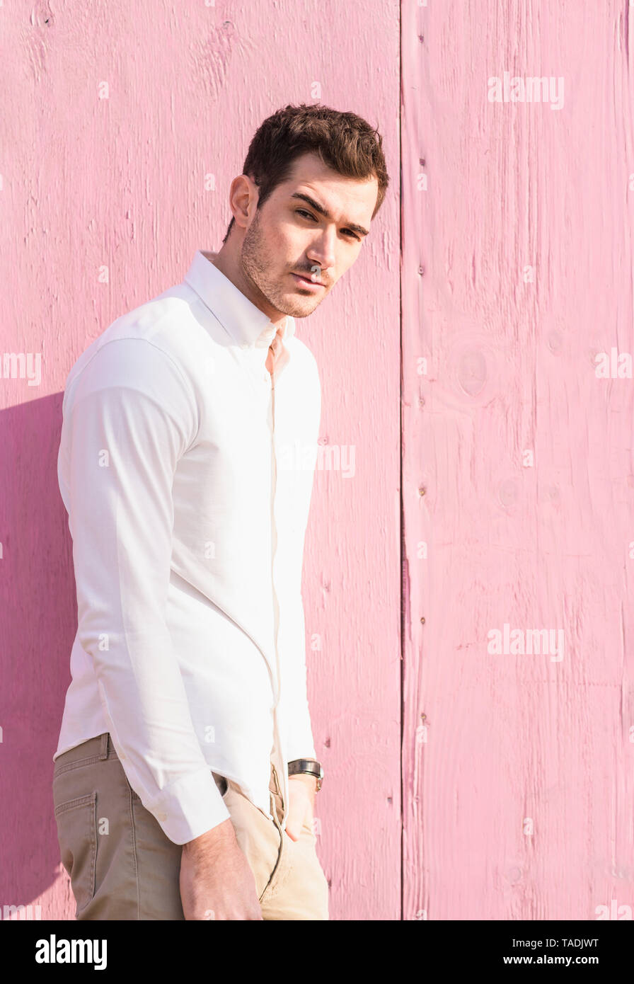Porträt der jungen Mann, der vor rosa Wand Stockfoto