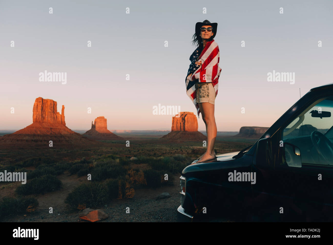 USA, Utah, Monument Valley, Frau mit Vereinigten Staaten von Amerika Flagge der Sonnenuntergang im Monument Valley genießen. Stockfoto