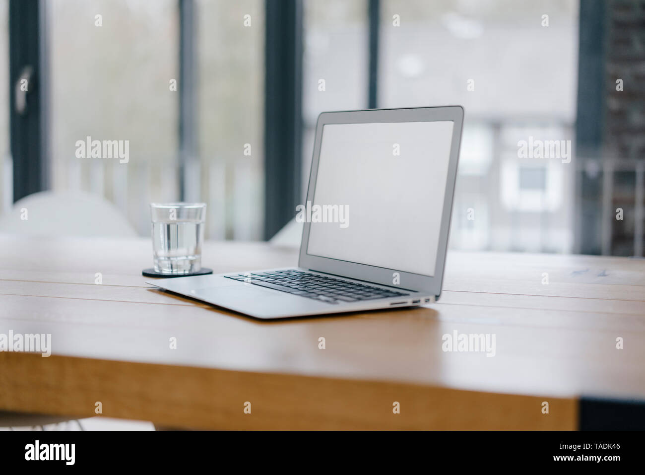 Laptop auf dem Schreibtisch im Büro mit Glas Wasser Stockfoto