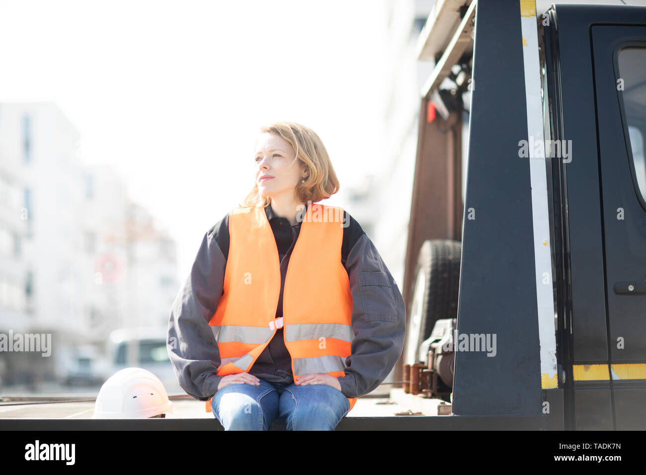 Frau mit Warnweste sitzen auf Lkw-Plattform Stockfoto