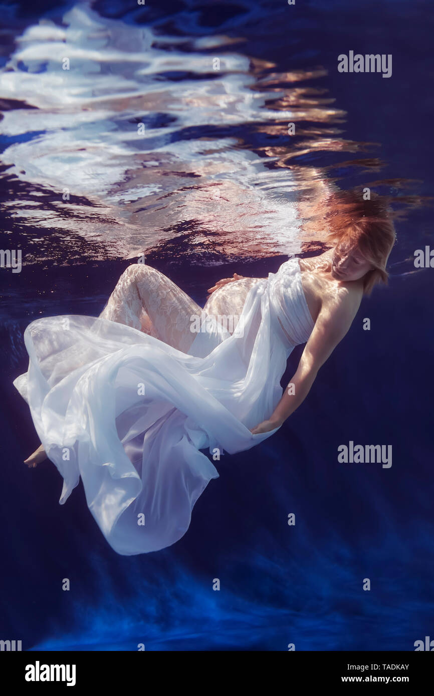 Schwangere Frau tragen weiße Kleid unter Wasser Stockfoto