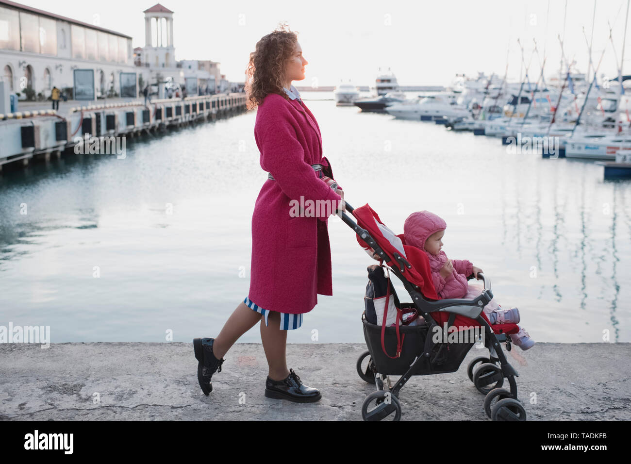 Mutter, Tochter im Kinderwagen an einem Jachthafen Stockfoto
