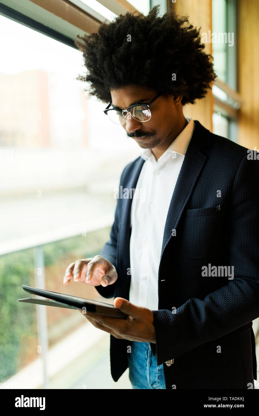 Unternehmer stehen am Fenster mit Tablet Stockfoto