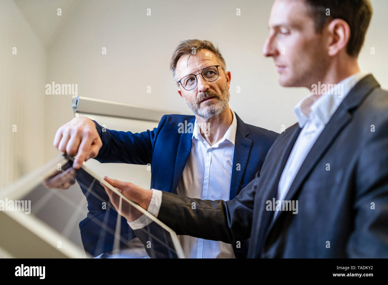 Zwei Geschäftsleute in Office mit Solarzelle diskutieren Stockfoto