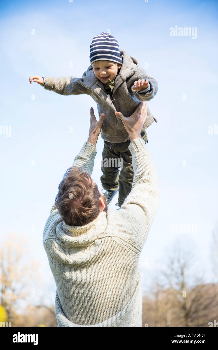 Vater werfen Happy Boy in der Luft unter blauem Himmel Stockfoto