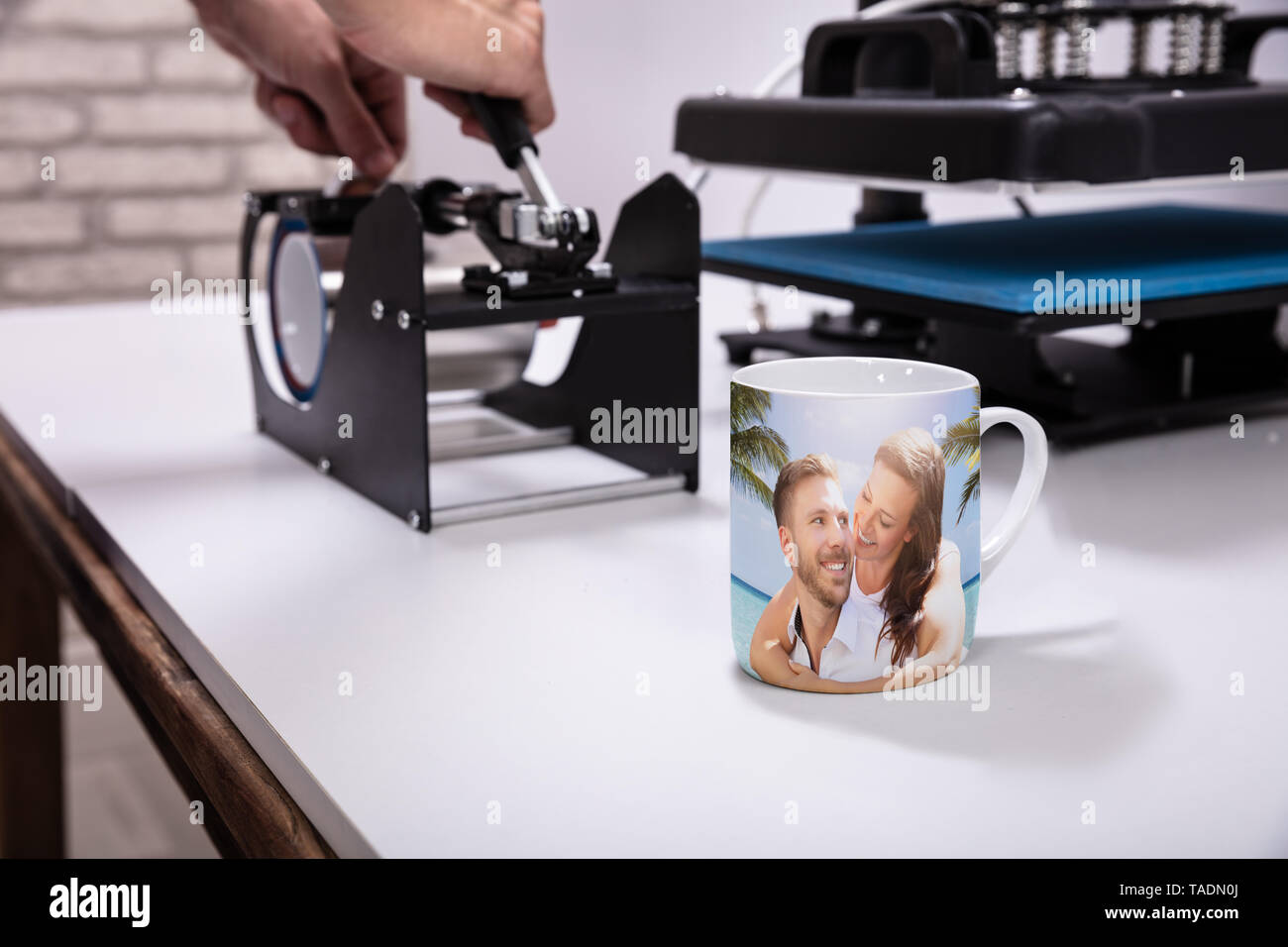 Man Druck auf Kaffeetassen in Werkstatt Stockfoto