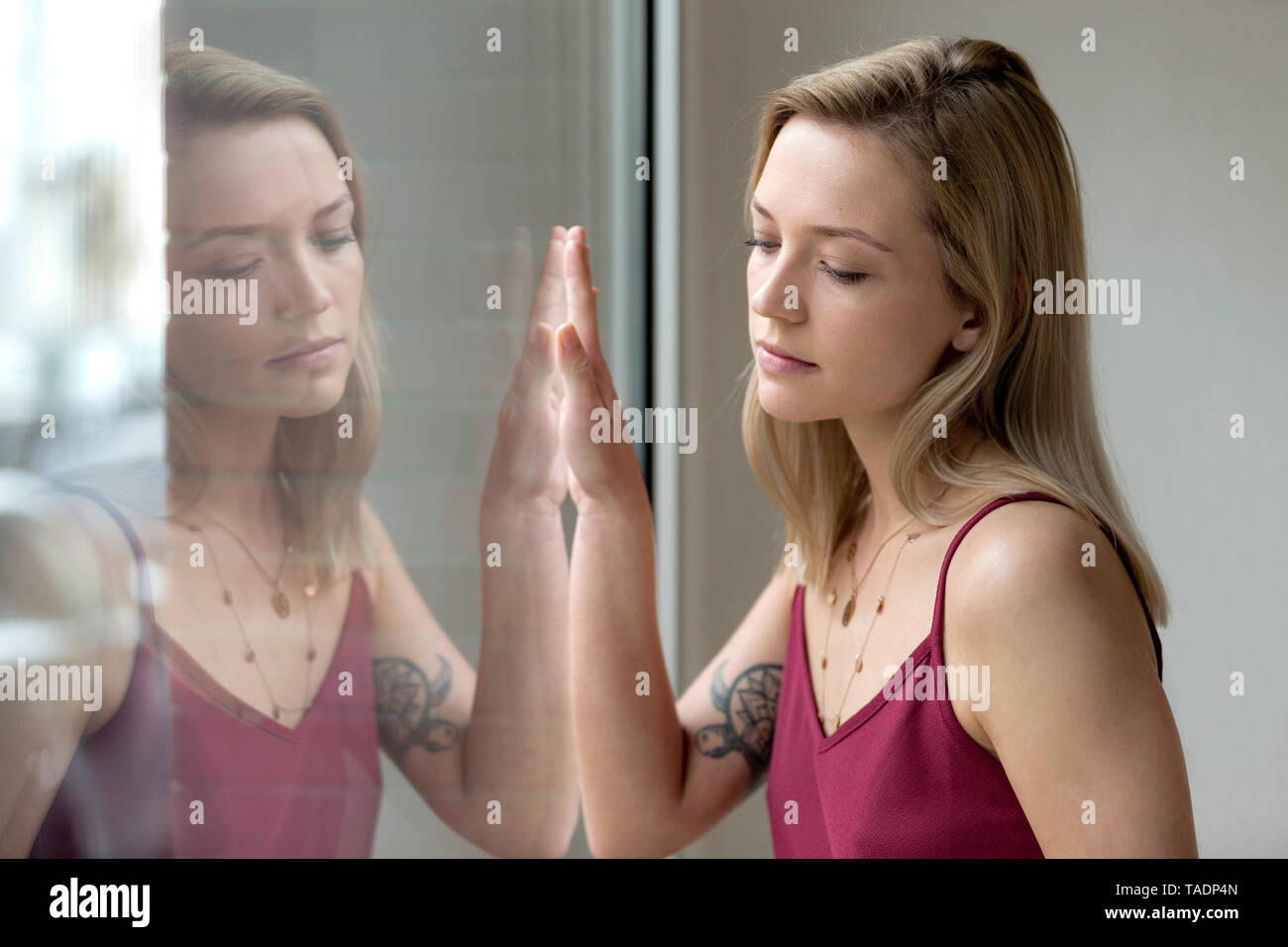 Porträt der blonde junge Frau und ihre Reflexion auf Fensterglas Stockfoto
