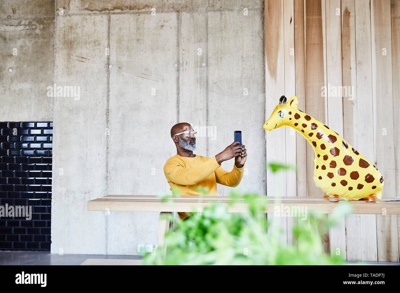 Reifen Geschäftsmann am Schreibtisch im Büro mit Handy und Giraffe Figur Stockfoto