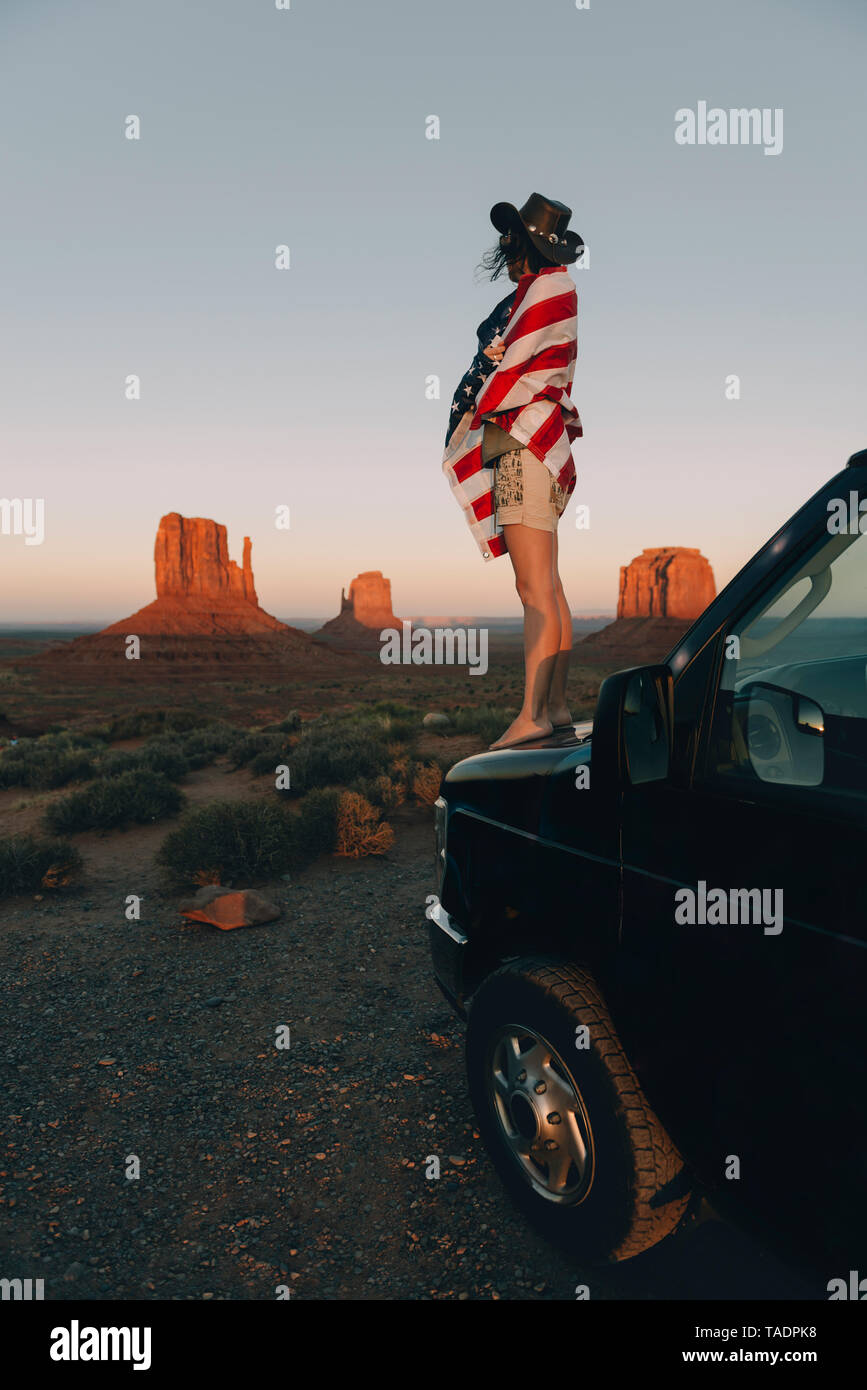 USA, Utah, Monument Valley, Frau mit Vereinigten Staaten von Amerika Flagge der Sonnenuntergang im Monument Valley genießen. Stockfoto