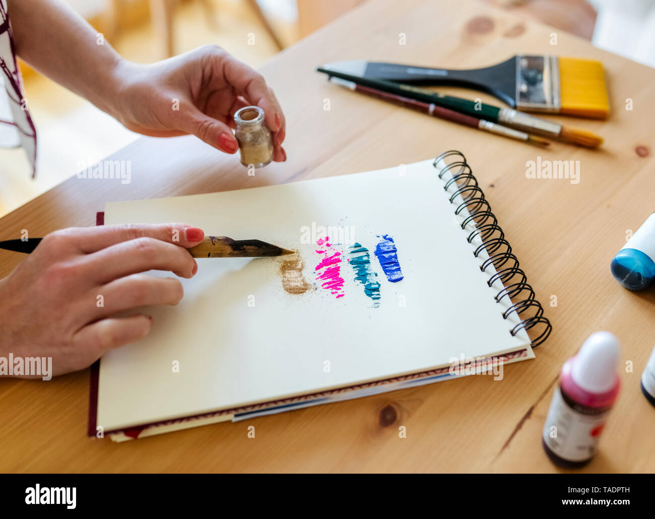 Woman's Hand Anwendung Farbpigmente auf Malbuch Stockfoto