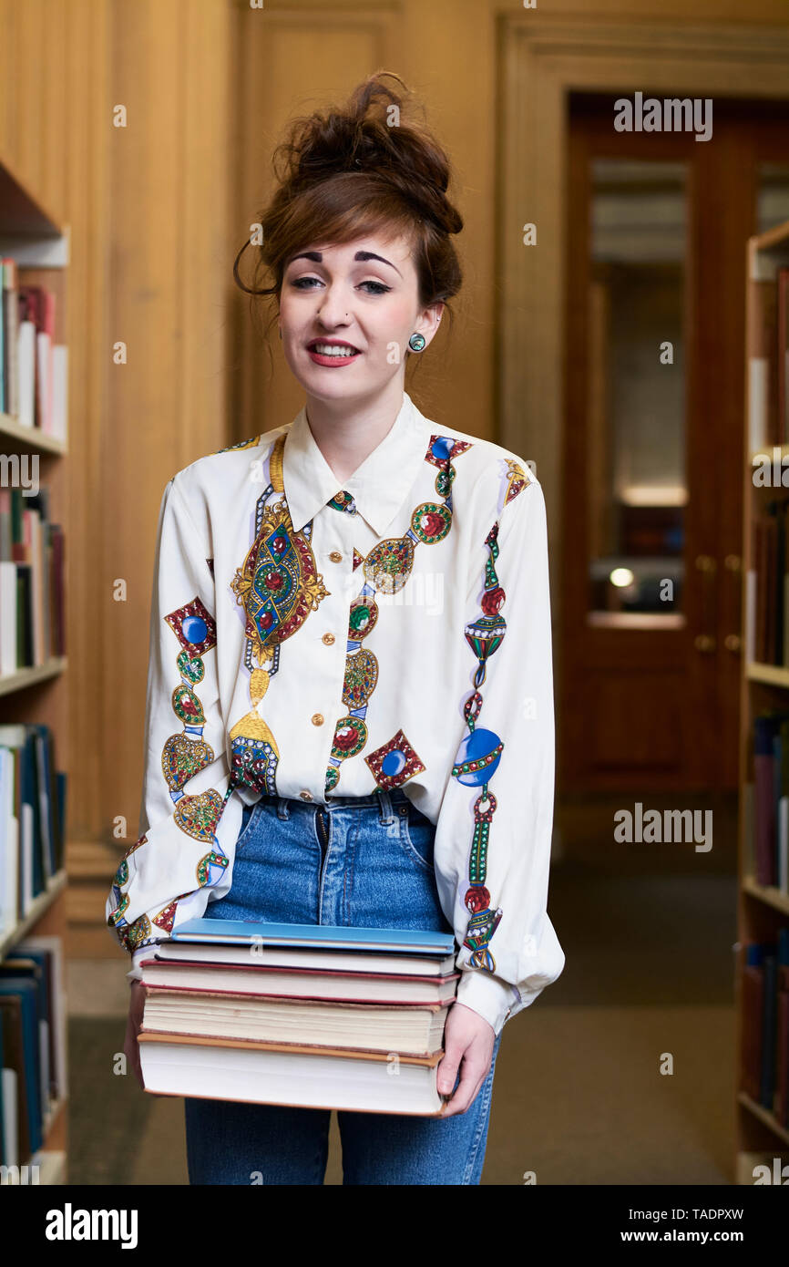 Studentin mit Bücher in einer öffentlichen Bibliothek Stockfoto