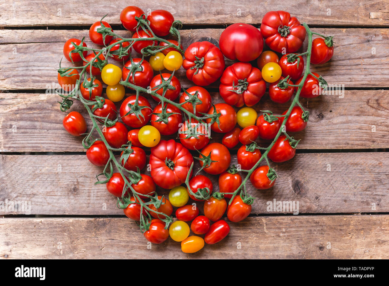 Verschiedene Sorten von Tomaten Gebäude Herz auf Holz Stockfoto