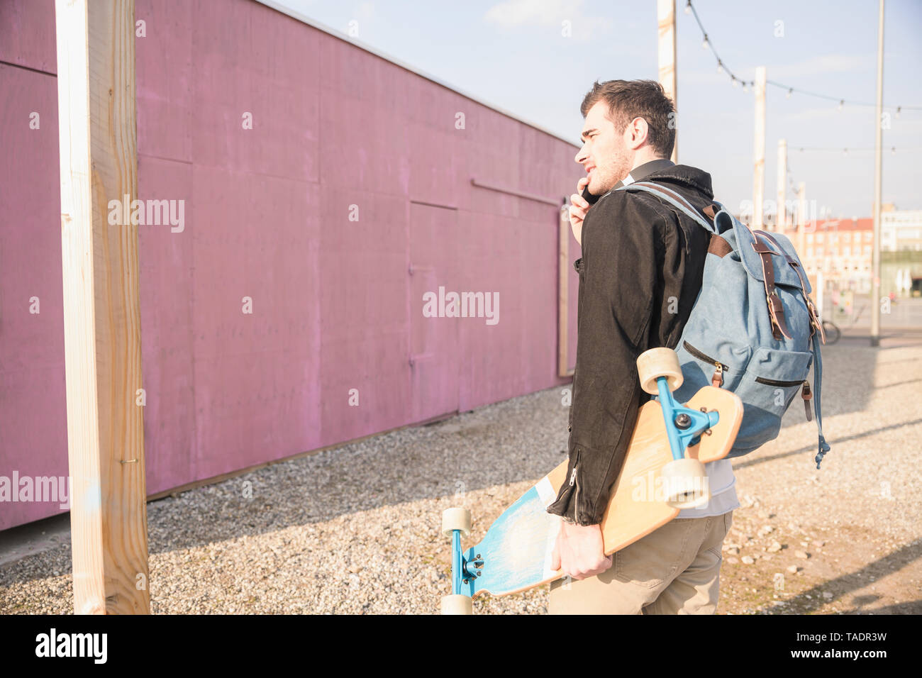 Junger Mann mit skatebaord und Handy Unterwegs in der Stadt Stockfoto