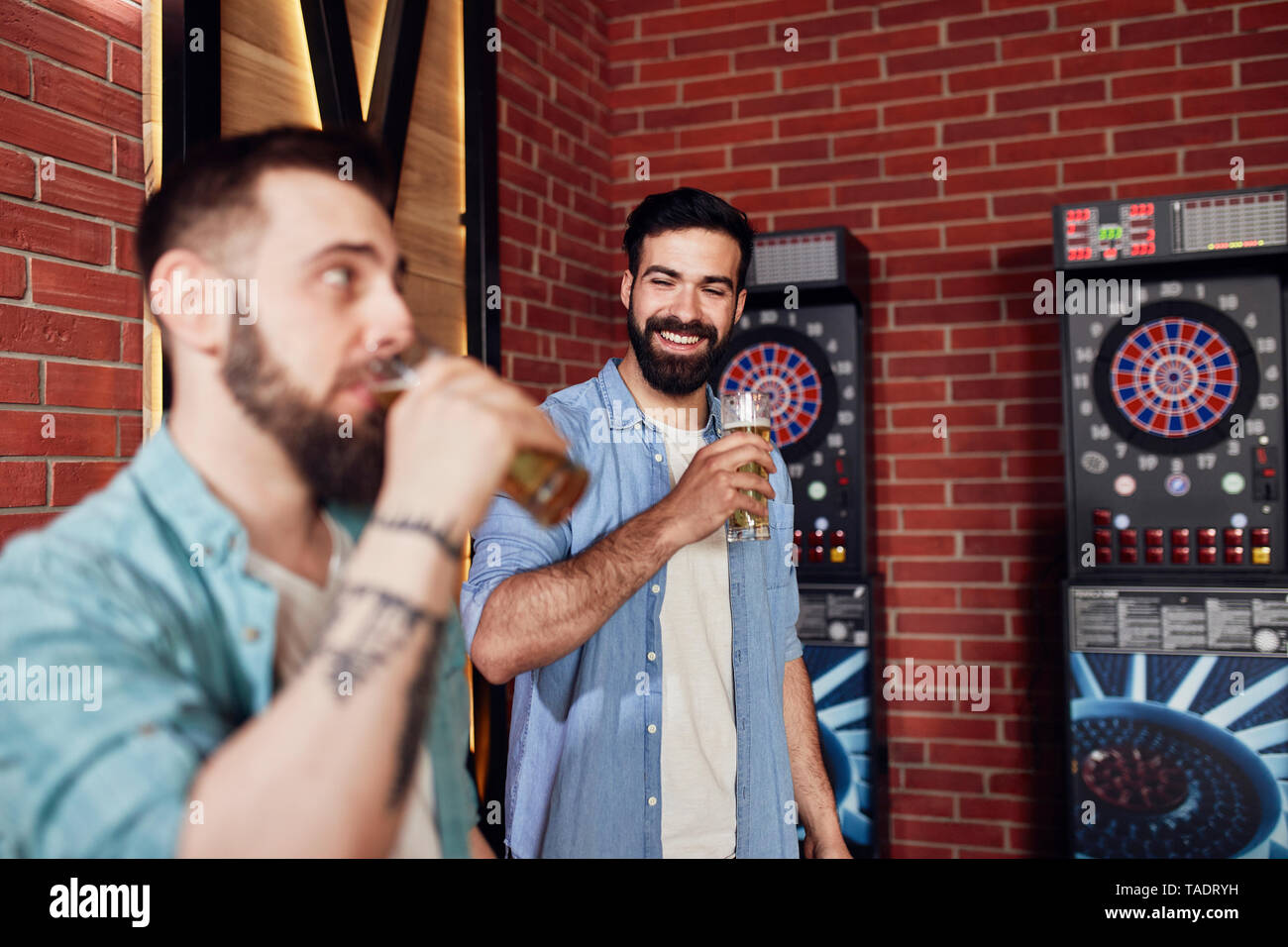 Zwei glückliche Freunde trinken Bier an der Dartscheibe in einem Pub Stockfoto