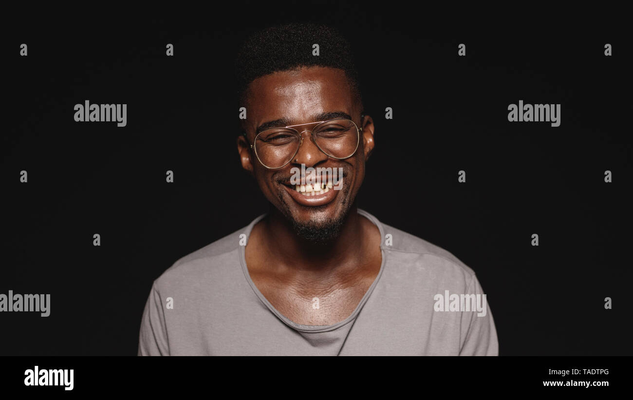 Lachend afrikanische Mann in Brillen auf schwarzem Hintergrund isoliert. Nahaufnahme einer glücklichen afrikanischen Mann an der Kamera schaut. Stockfoto